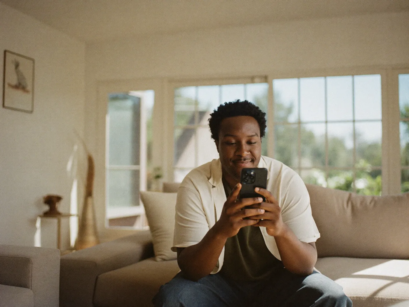 A homeowner relaxing at home while checking their project status on a smartphone